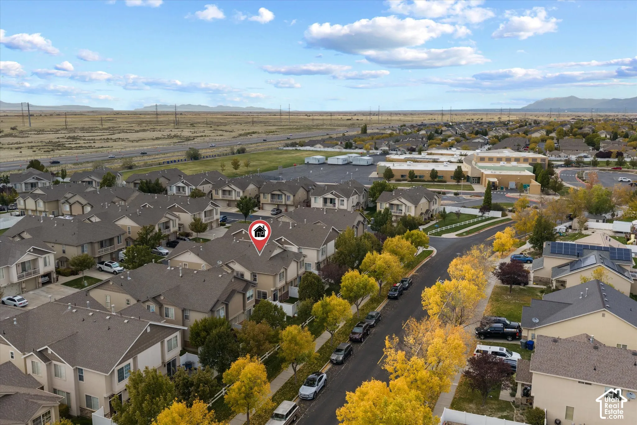 Aerial perspective of a multi-level residence featuring a pitched roofline, neutral exterior siding, and a rear-facing yard with perimeter fencing