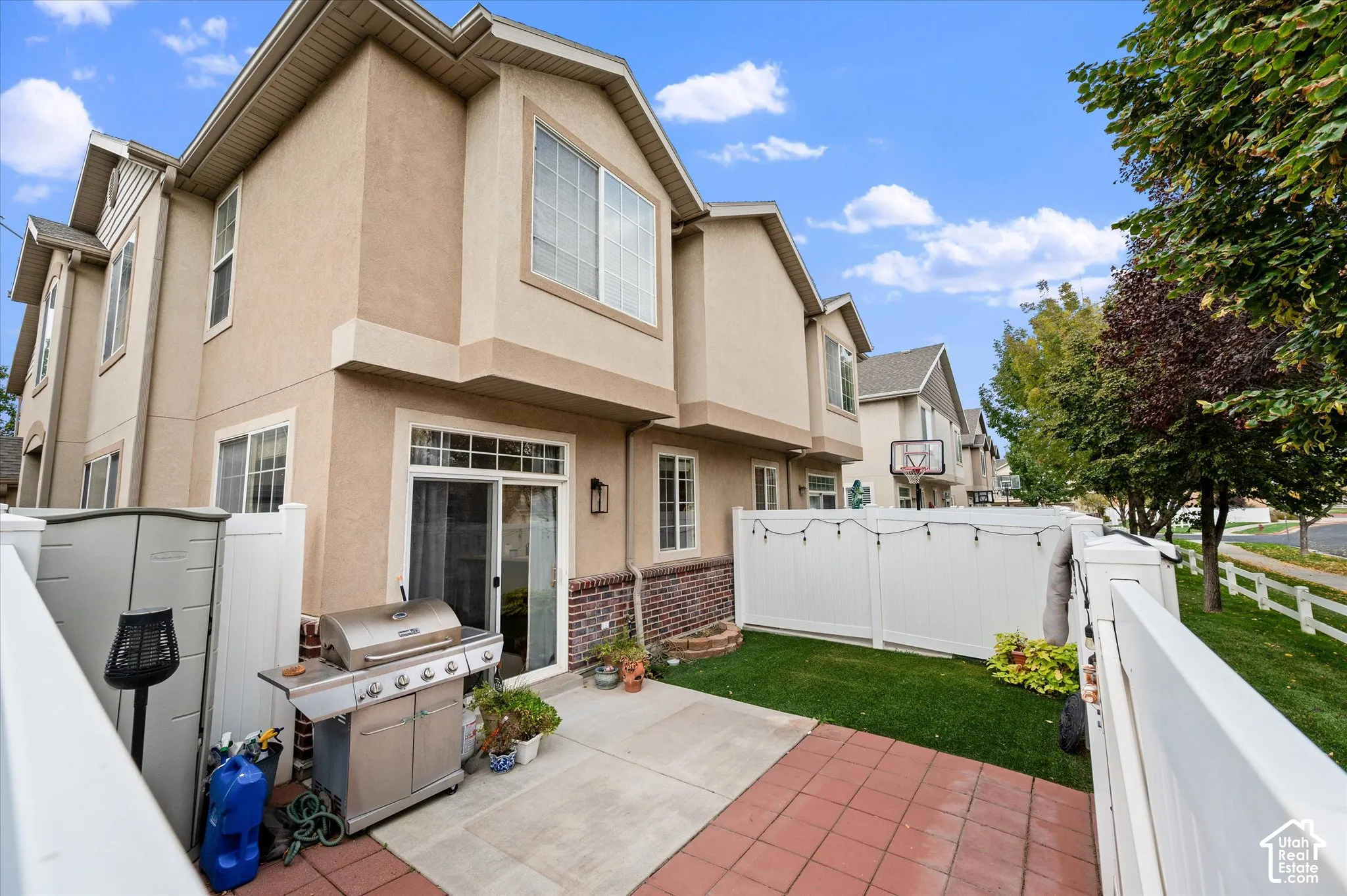Exterior features include a stucco facade with brick accents, a private fenced yard, and a paved patio area