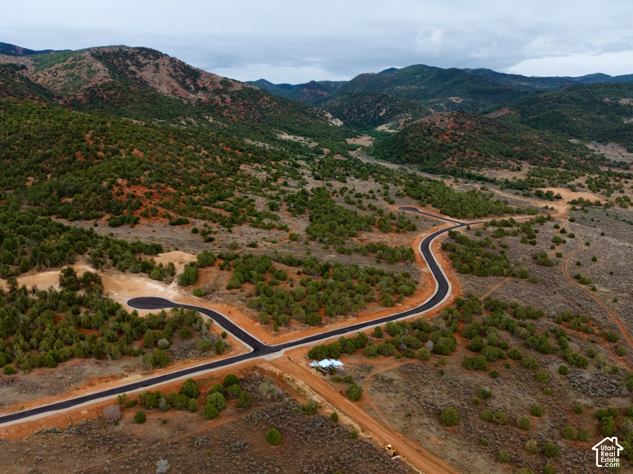Expansive acreage featuring paved roads, undulating terrain, native vegetation, and a prominent mountain backdrop