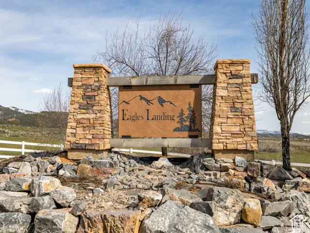 Community monument sign featuring dual stacked-stone pillars, timber framing, and metallic signage set against a mountain backdrop