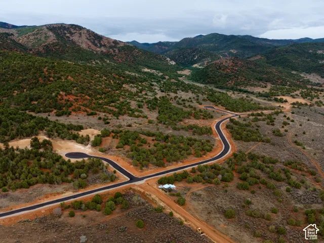 Expansive acreage featuring paved roads, undulating terrain, native vegetation, and a prominent mountain backdrop