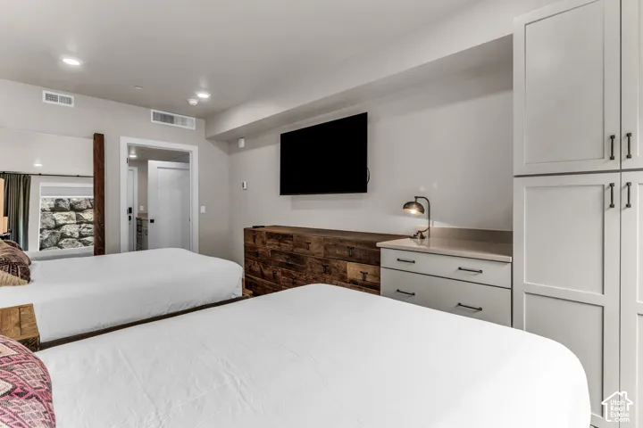 Built-in light gray cabinetry, custom rustic wood-finish media console, and recessed ceiling lighting