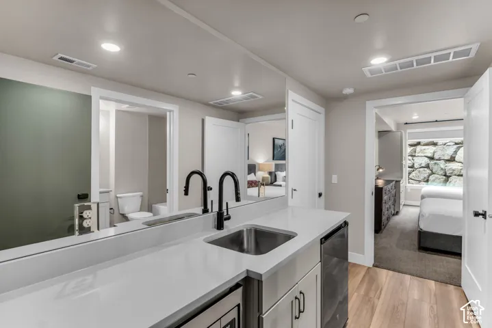 Wet bar featuring a solid-surface countertop, under-mount stainless steel sink, matte black gooseneck faucet, and recessed ceiling lighting