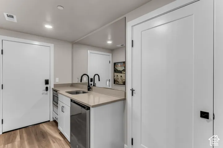 Wet bar featuring white shaker-style cabinetry, quartz countertop, integrated stainless steel sink, matte black gooseneck faucet, and built-in microwave