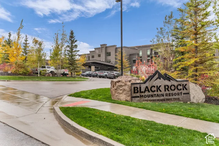 Exterior facade featuring dark-toned masonry, multi-story structure with balconies, concrete paved drive, and stone monument signage