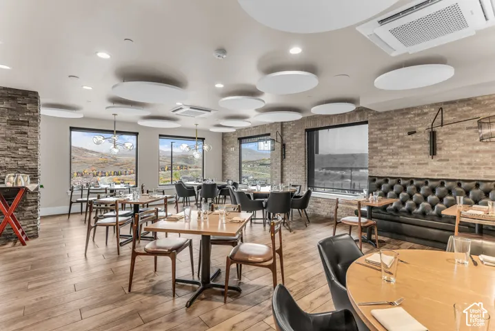 Spacious interior featuring exposed brick walls, stone veneer accents, wood-finish flooring, custom circular acoustic ceiling panels, and floor-to-ceiling windows