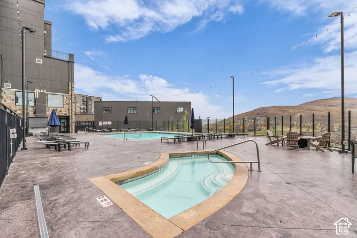 Outdoor pool area featuring a stamped concrete deck, in-ground spa with steps, rectangular swimming pool, and mountain backdrop