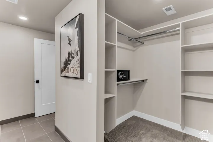 Walk-in closet featuring custom built-in shelving, integrated hanging rods, recessed ceiling lighting, and a built-in security safe