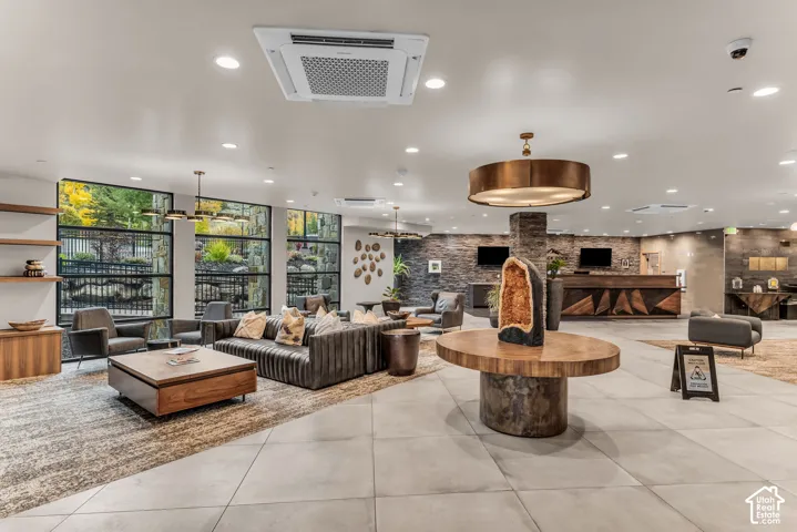 Open-concept floor plan featuring large-format tile flooring, textured stone accent wall, floor-to-ceiling windows, and recessed ceiling lighting