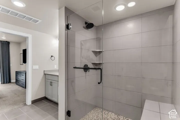 Walk-in shower featuring large-format wall tile, a glass enclosure, a built-in tiled bench, stone-composite mosaic floor tile, and matte black fixtures
