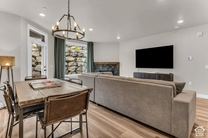 Open-concept interior featuring wood-finish flooring, a tiered metal chandelier, and a stone fireplace with a wooden mantel
