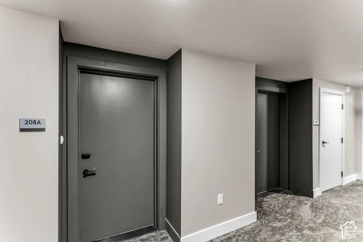 Neutral-toned interior hallway featuring charcoal-finished solid-core doors, black hardware, and patterned resilient flooring