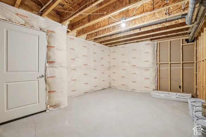 Unfinished lower level featuring concrete flooring, exposed wooden ceiling joists, and insulated perimeter walls