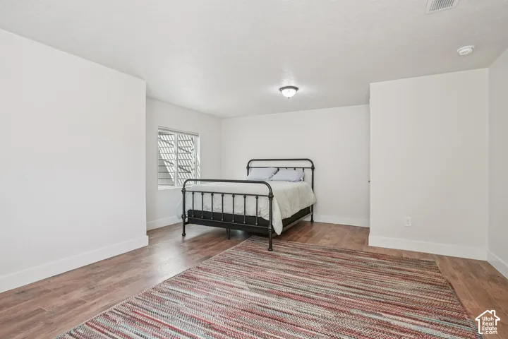 Wood-finish flooring, neutral walls, and a single-pane window with horizontal blinds