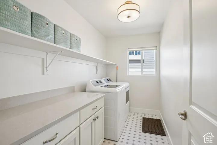 Laundry room featuring white shaker-style cabinetry, a solid-surface countertop, patterned tile flooring, and integrated wall shelving