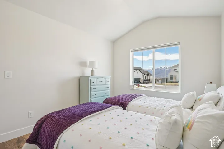 Vaulted ceilings, wood-finish flooring, and a large window featuring mountain scenery