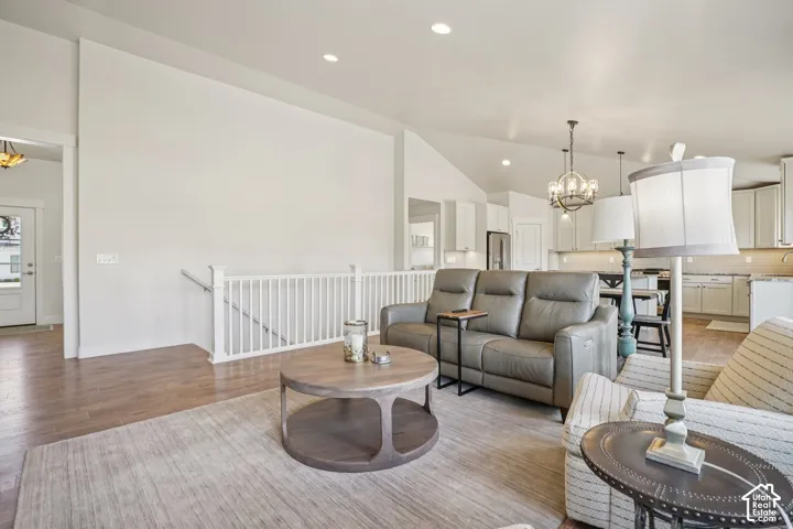 Vaulted ceilings, wood-finish flooring, white spindle staircase railing, and recessed lighting