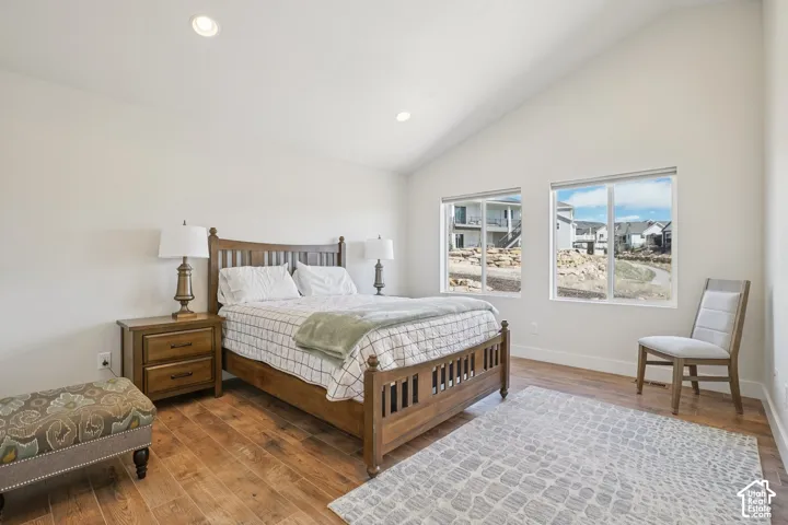 Vaulted ceiling, recessed lighting, and wood-finish flooring