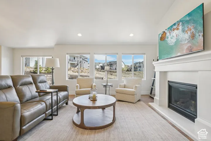 Living area featuring a floor-to-ceiling fireplace mantel, recessed lighting, expansive windows, and wood-finish flooring