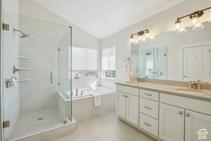 Double vanity with solid surface countertops, glass-enclosed walk-in shower with tiled surround, and integrated soaking tub with stone-style tile finish