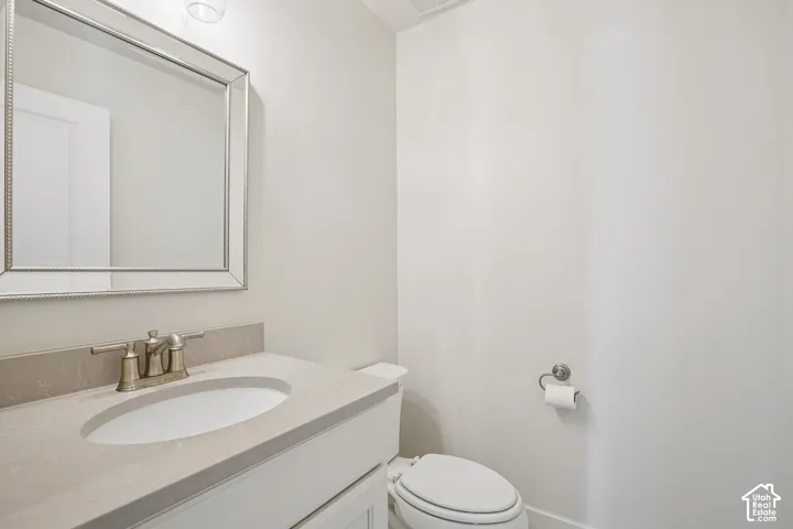 Neutral-toned vanity with a stone-composite countertop, undermount sink, metallic dual-handle faucet, and an integrated framed mirror