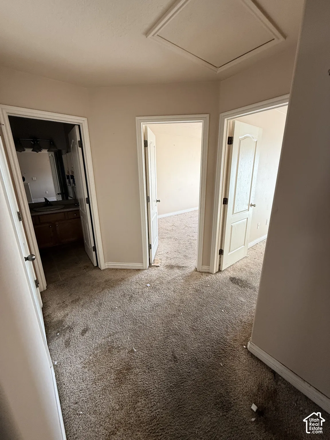Hallway featuring carpeting, solid-core interior doors, and attic access panel