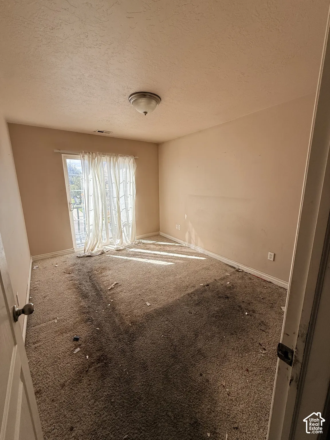 Room featuring wall-to-wall carpeting, a flush-mount ceiling light fixture, and a sliding glass door