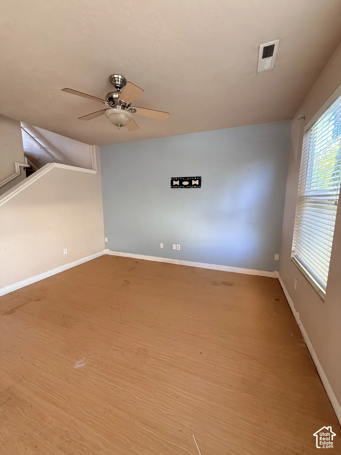 Interior space featuring wood-finish flooring, a ceiling fan with integrated lighting, and horizontal window blinds