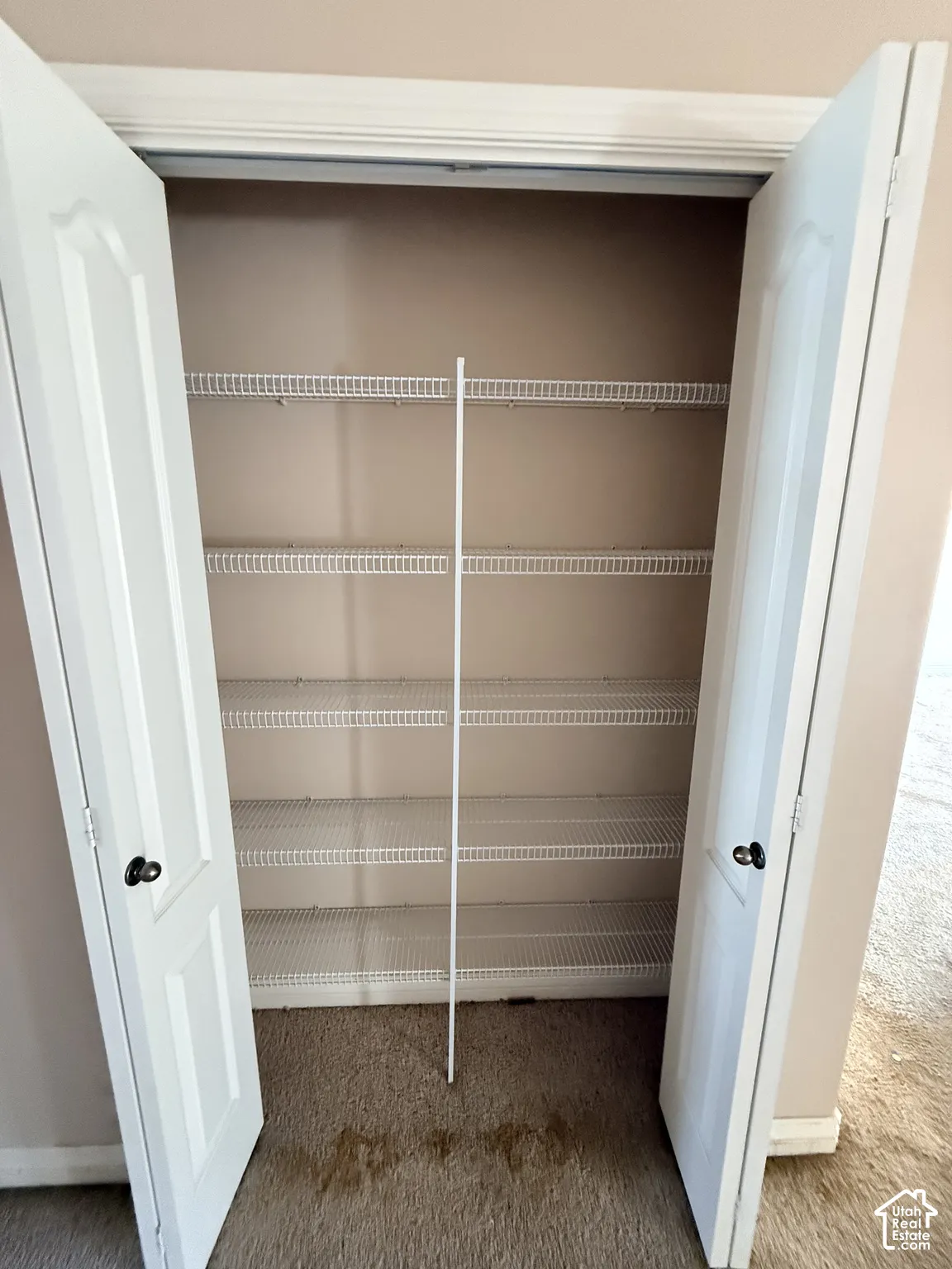 Built-in closet featuring white paneled double doors and five-tier wire shelving