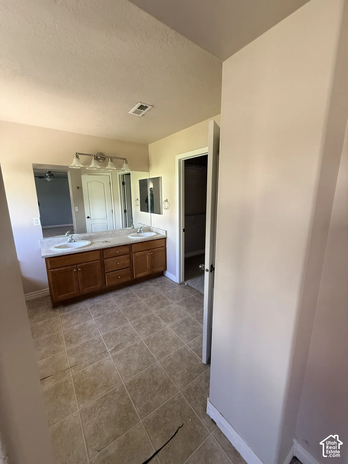 Double vanity featuring wood cabinetry, stone-finish countertops, dual integrated sinks, and ceramic tile flooring