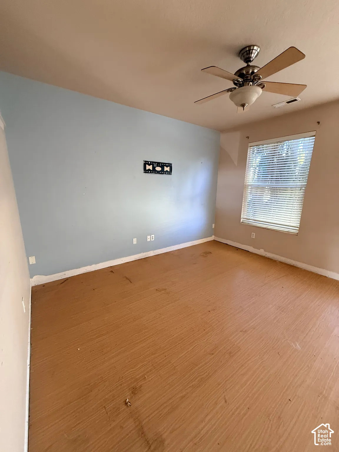 Interior space featuring wood-finish flooring, a ceiling fan with integrated light fixture, and horizontal window blinds