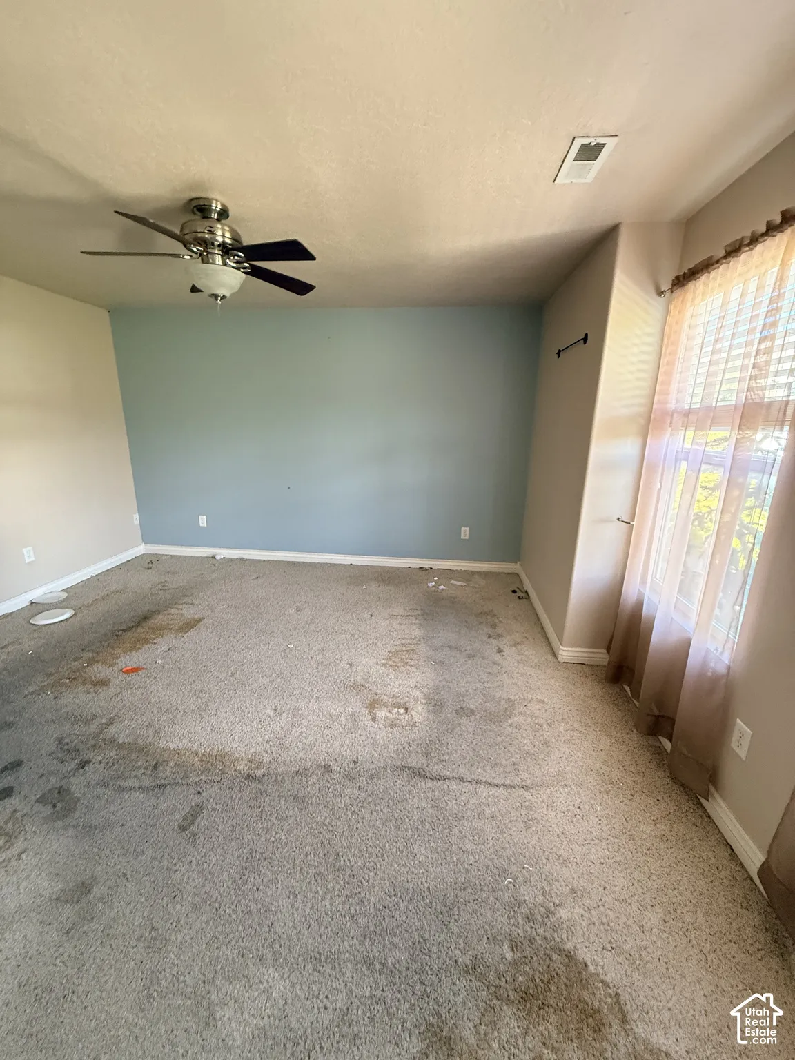 Room featuring an accent wall, wall-to-wall carpeting, and a ceiling fan with integrated lighting