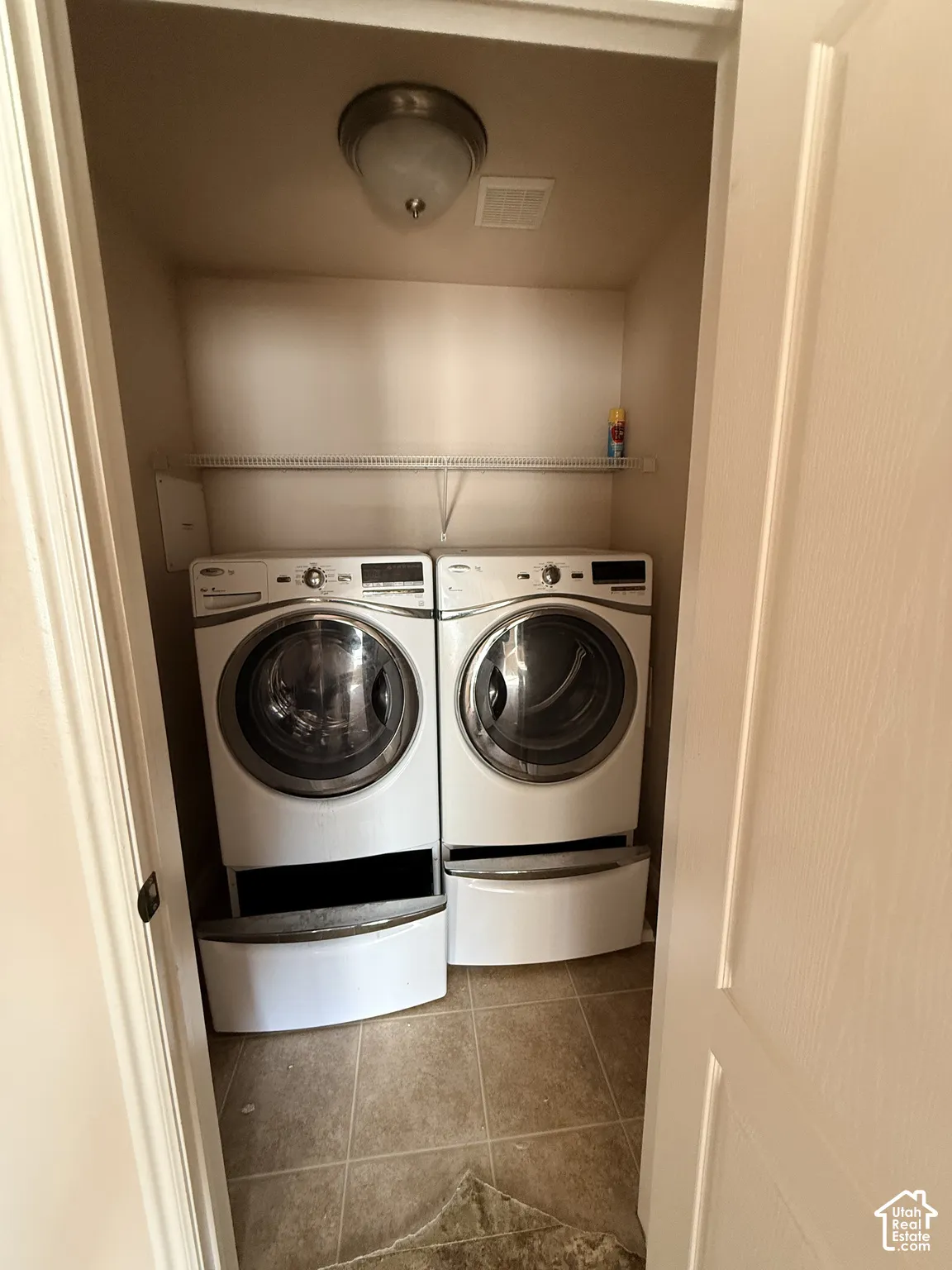 Laundry area featuring large-format ceramic tile flooring, built-in wire shelving, and a dome-style overhead light fixture
