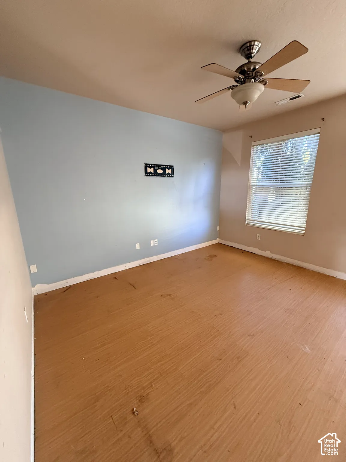 Room featuring wood-finish flooring, a multi-blade ceiling fan with an integrated light fixture, and horizontal window blinds