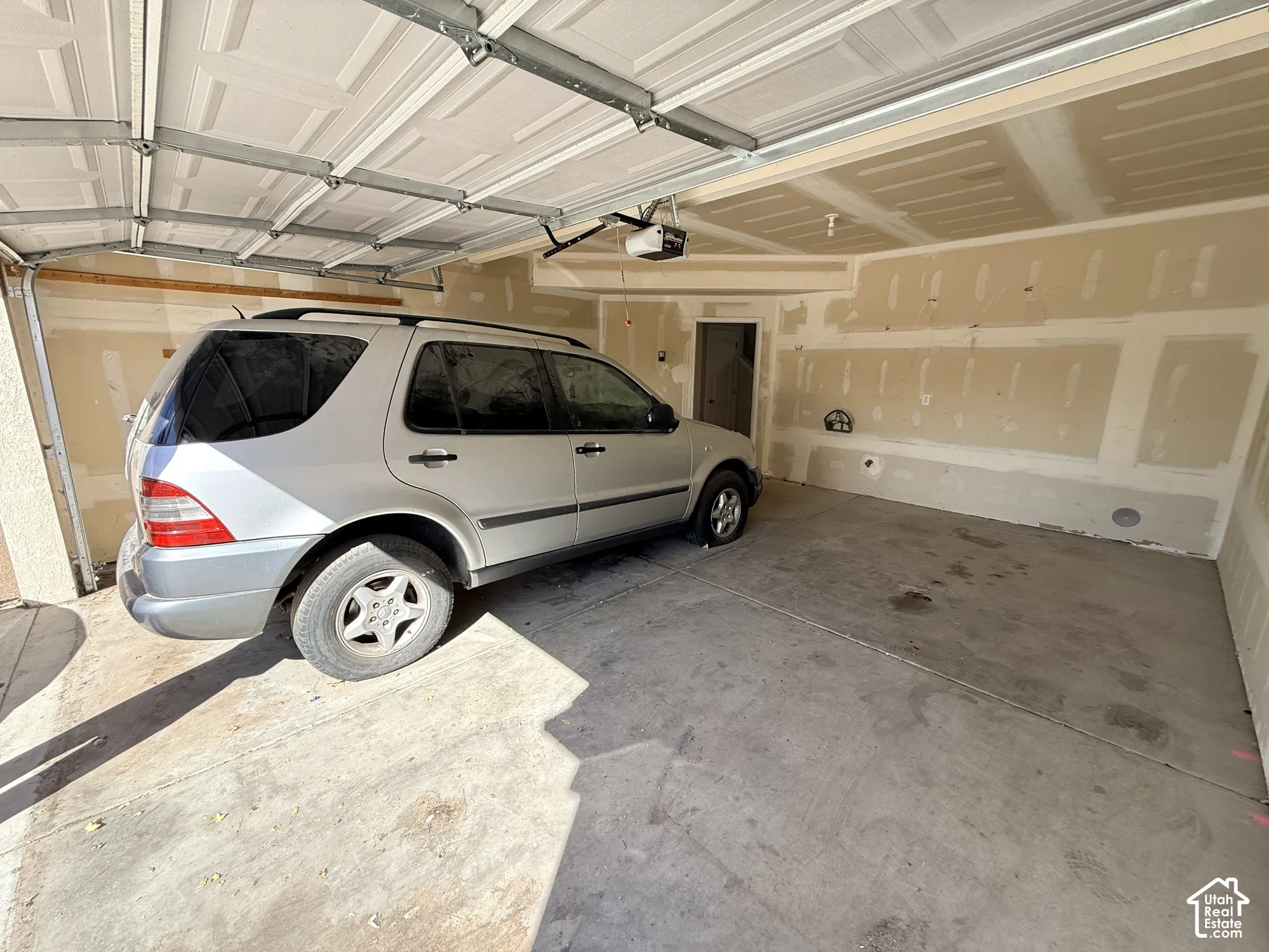 Attached two-car garage featuring a concrete floor, sectional overhead garage door, and motorized door opener