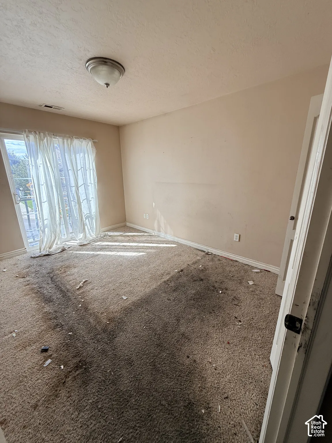 Room featuring wall-to-wall carpeting, sliding glass doors, and a flush-mount ceiling light fixture