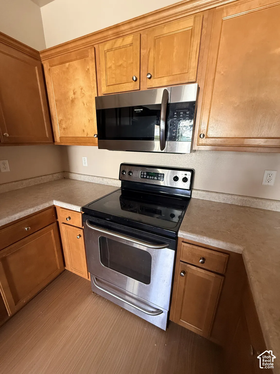Kitchen featuring wood-finish cabinetry, solid-surface countertops, and a stainless steel over-the-range microwave and electric range