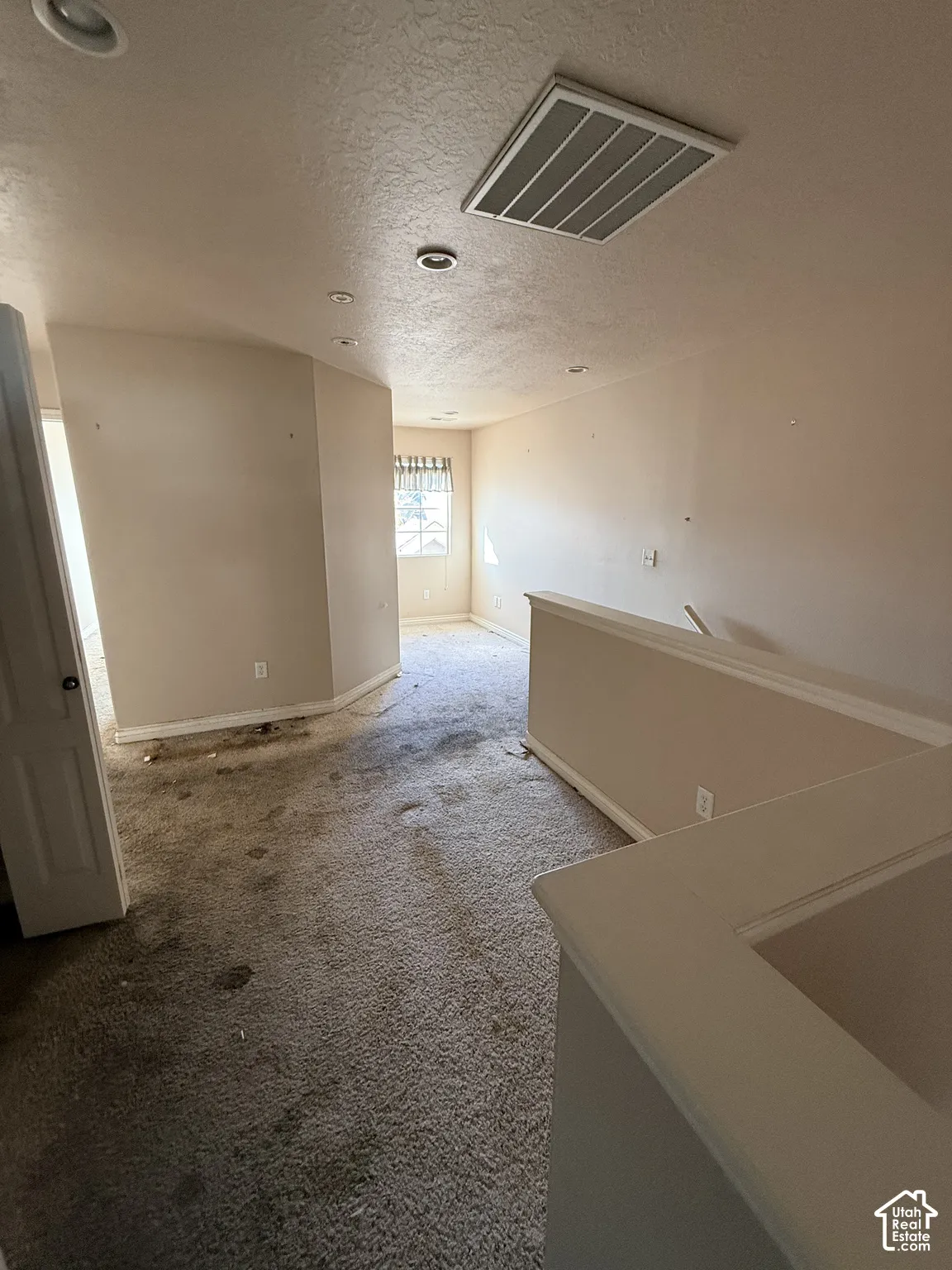 Open-concept area featuring neutral wall paint, carpeting, recessed lighting, and a partial-height wall with a cap rail