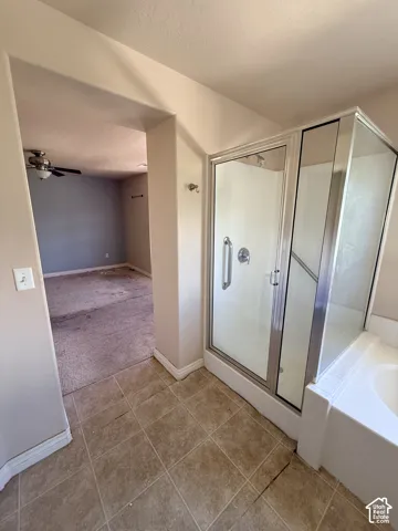 Standalone shower stall with a glass enclosure, chrome fixtures, and tiled flooring