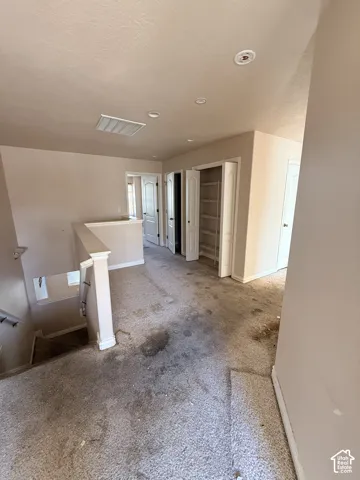 Interior landing area featuring neutral wall paint, recessed lighting, carpeted flooring, built-in shelving, and multiple interior doors