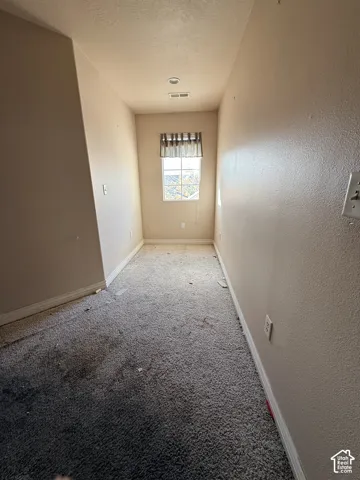 Neutral-toned room featuring wall-to-wall carpeting and a single window with grid detailing