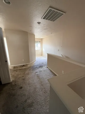 Open-concept area featuring neutral wall paint, carpeting, recessed lighting, and a partial-height wall with a cap rail