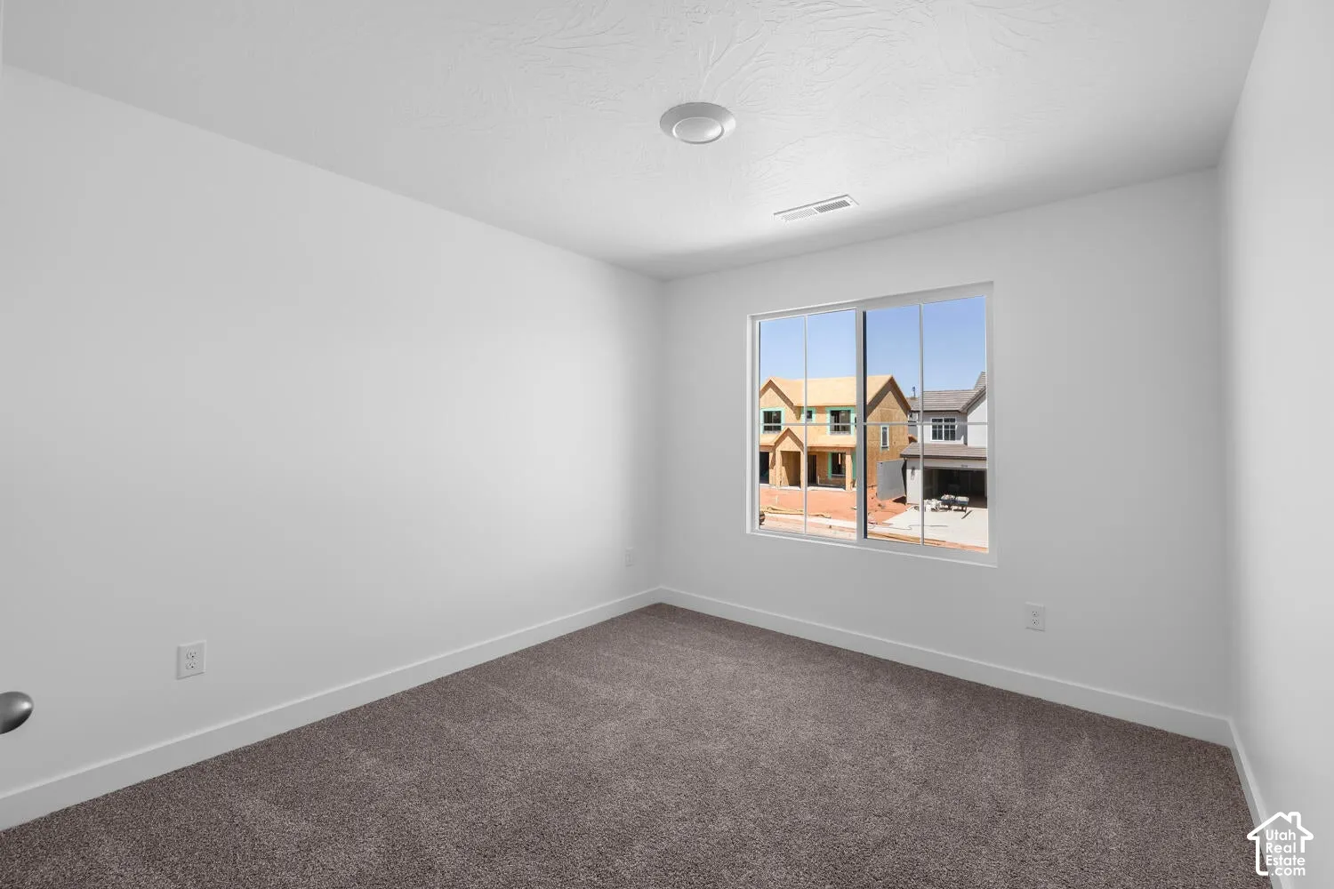 Neutral-toned room featuring neutral carpeting, white walls, and a large window with sliding glass panes