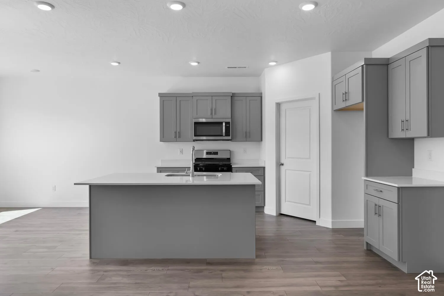 Kitchen featuring grey shaker-style cabinetry, quartz countertops, a central island, recessed lighting, and wood-finish flooring