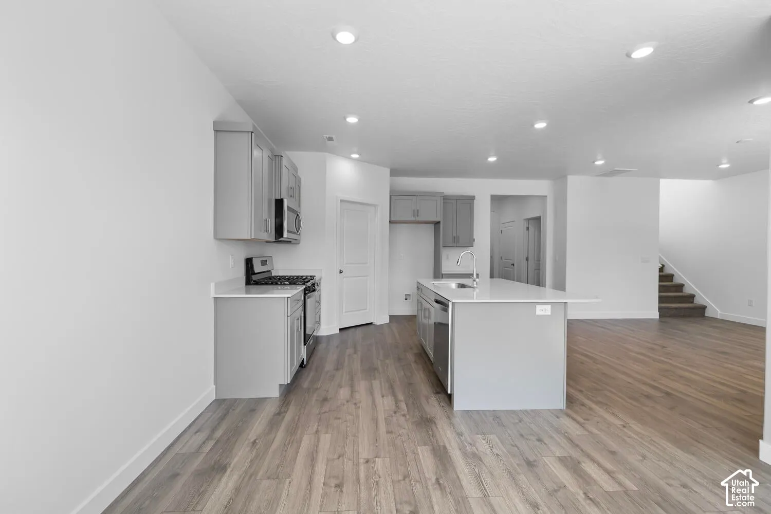 Kitchen featuring shaker-style cabinetry, a central island with a solid-surface countertop, recessed lighting, and wood-finish flooring