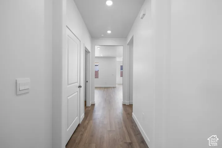 Hallway featuring wood-finish flooring, recessed lighting, and crisp white interior doors