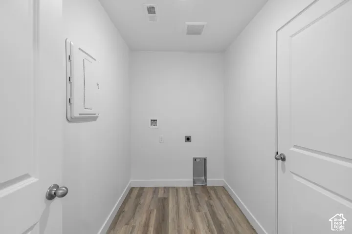 Dedicated utility room featuring wood-finish flooring, two solid-core interior doors, and recessed laundry hookups