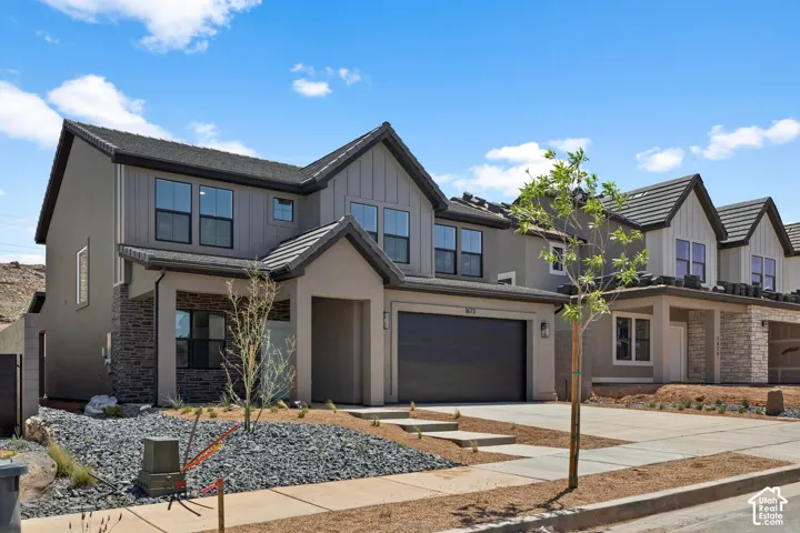 Multi-level exterior featuring stucco and vertical siding, stacked stone accents, a dual-pitch roofline with concrete tiles, and an attached two-car garage