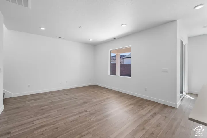 Neutral interior space featuring wood-finish flooring, recessed lighting, and a window with exterior mountain scenery