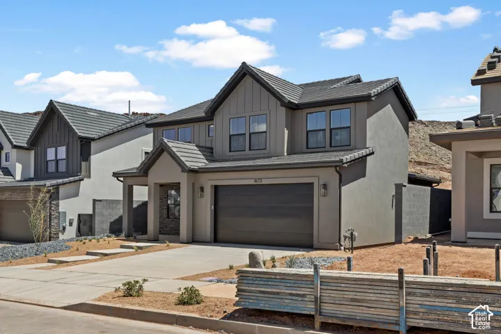 Two-story exterior featuring a grey stucco facade, vertical siding accents, dark-toned concrete roof tiles, and an attached two-car garage
